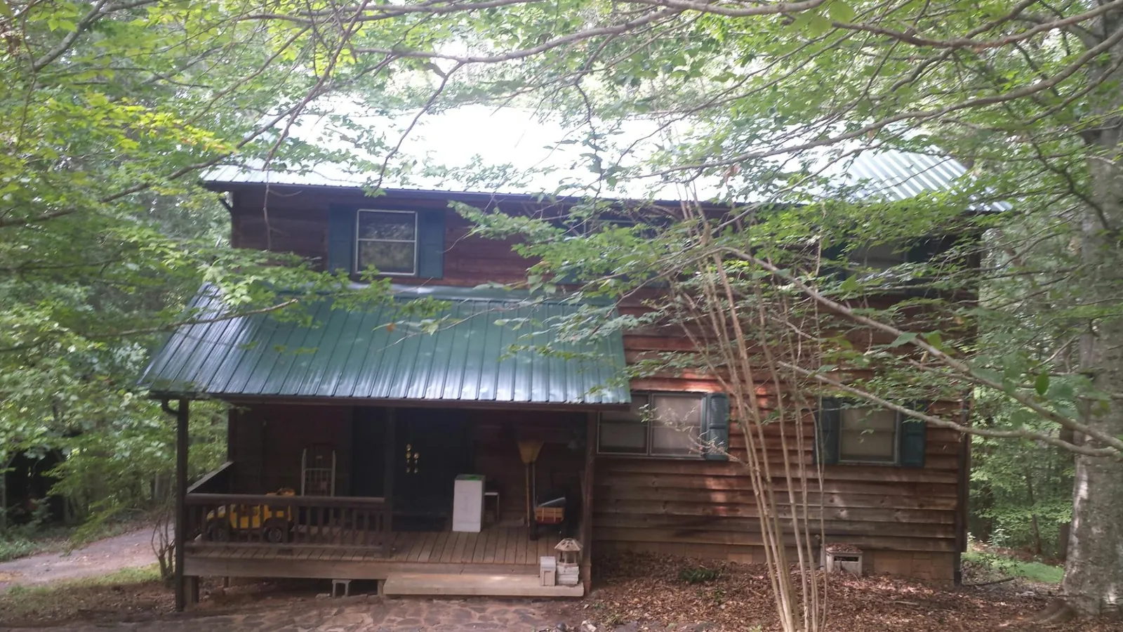 Green metal roof and covered porch on a log cabin in Carthage